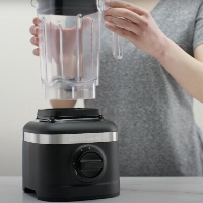 Person removing blender jar from black base of KitchenAid® blender